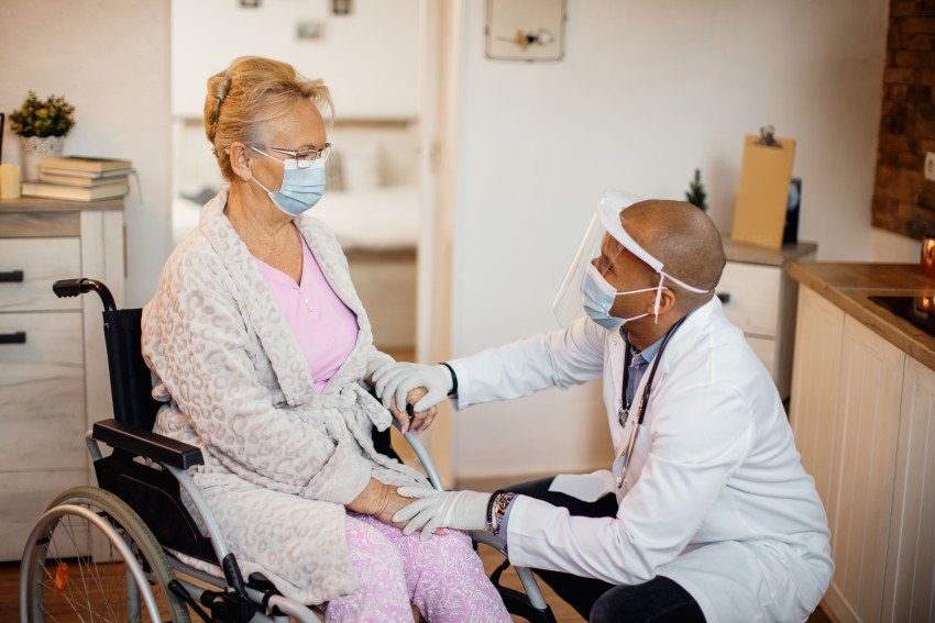 Doctor caring for a senior woman in a wheelchair at a nursing home