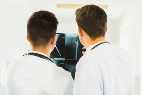 Radiology doctors examining X-ray images on a monitor in a medical clinic.